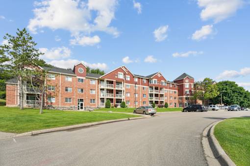 A large red brick apartment building with a car parked in front.