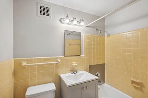A bathroom with yellow tiles and a white toilet.