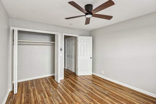 A room with a ceiling fan and wooden floors.