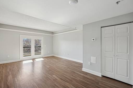 A room with wooden floors and white walls, with a door on the right side.