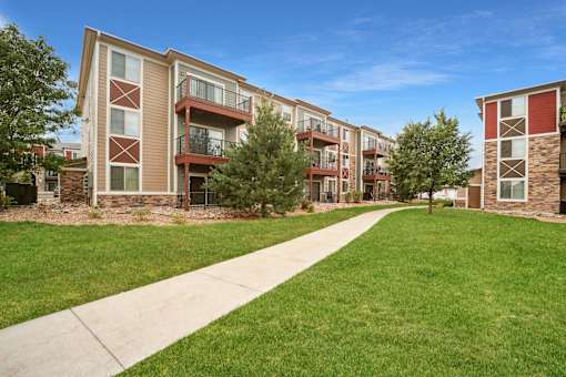 Apartment buildings with balconies and a sidewalk in front.