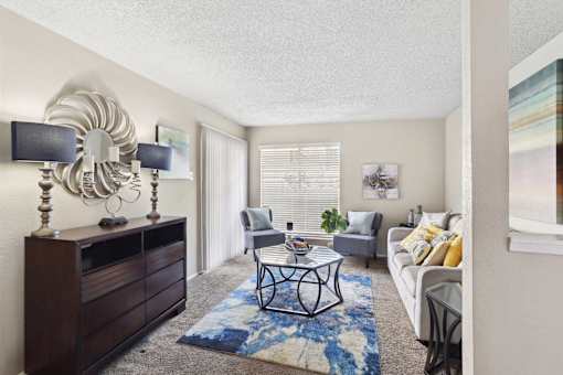 A living room with a white couch, a coffee table, and a large mirror on the wall.