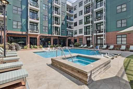 A large outdoor swimming pool with a wooden deck and lounge chairs.