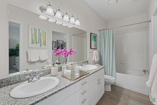 A white bathroom with a sink, mirror, and shower.