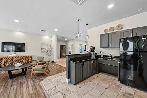 A modern kitchen with black appliances and wooden floors.