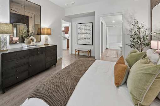 A bedroom with a large bed and a dresser with a mirror above it.