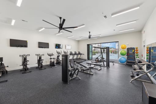 a gym with treadmills and other exercise equipment in a building with a window
