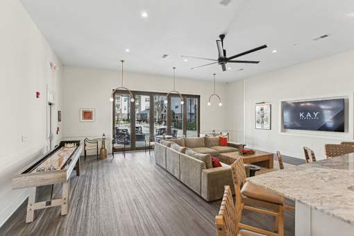 A spacious living room with a pool table and a kitchen area.