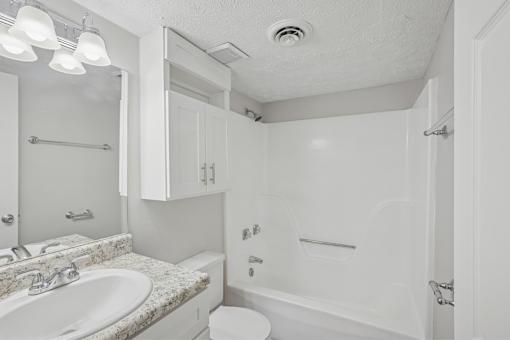 A white bathroom with a sink, toilet, and bathtub.