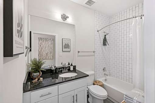 A bathroom with a black granite countertop and white tiles.