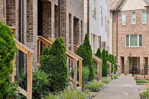 A row of houses with green trees in front.