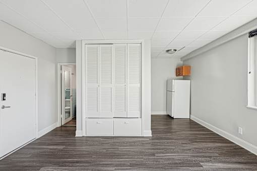 A room with white walls and a wooden floor with a white door and a white cabinet with a box on top of it.