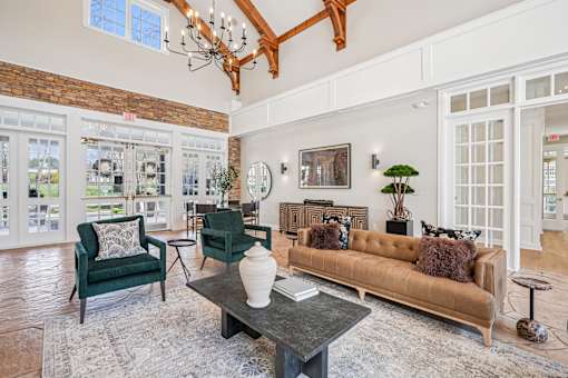 A living room with a brown couch, green chairs, and a coffee table.