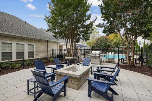an outdoor patio with blue chairs and a fire pit