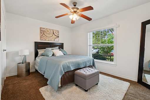 A bedroom with a bed, a ceiling fan, and a window.