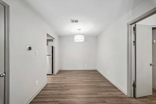 A long, empty hallway with wood flooring and white walls.