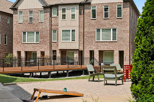A brick building with a balcony and chairs in front.
