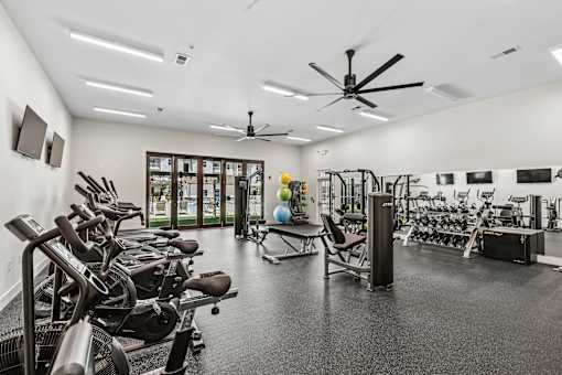 A spacious gym with a variety of equipment and a ceiling fan.