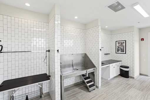 A white tiled bathroom with a sink, mirror, and a bench.