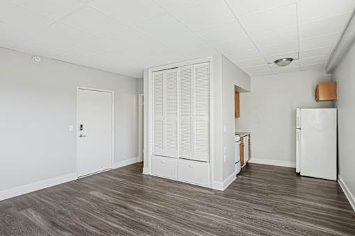 A kitchen area with a white fridge, white cabinets, and a white door.