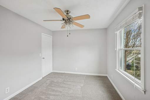 A room with a ceiling fan and a window.