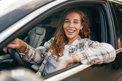 A woman with curly hair is driving a car.