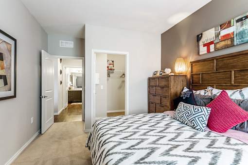A bedroom with a patterned bedspread and a wooden dresser.