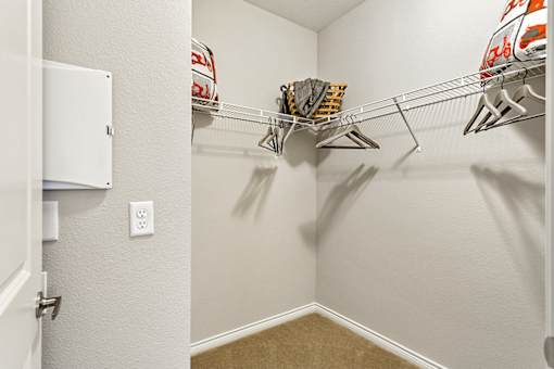 A white closet with a shelf and a white door.