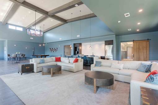A spacious living room with white furniture and a large rug.