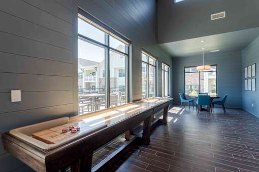 A long wooden table is in the middle of a room with a blue chair and a window.