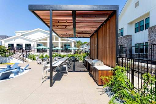 A patio with a table and chairs under a wooden roof.