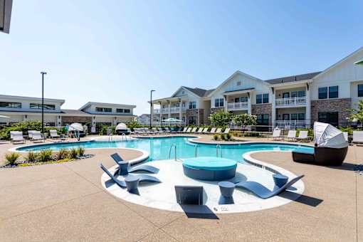 A large outdoor swimming pool surrounded by lounge chairs and umbrellas.