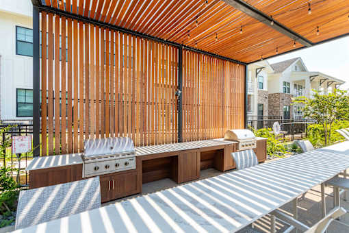 A wooden grill is on a patio with a grill cover.