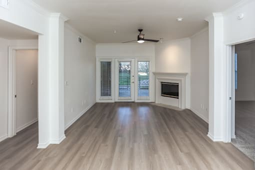 A spacious room with a ceiling fan and a fireplace.