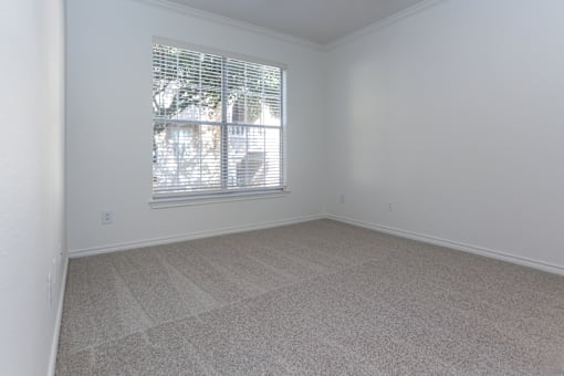 A room with a window covered by white blinds.