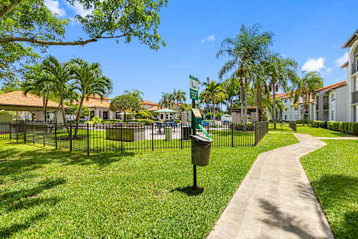 A sunny day at a park with a pathway and a mailbox.