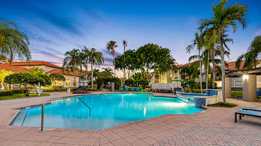 A swimming pool surrounded by palm trees and a bench.