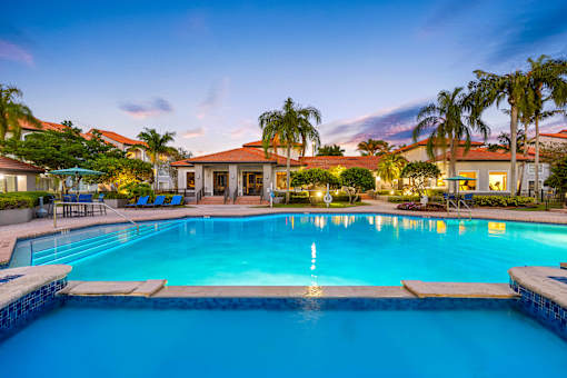 A swimming pool surrounded by palm trees and a house.