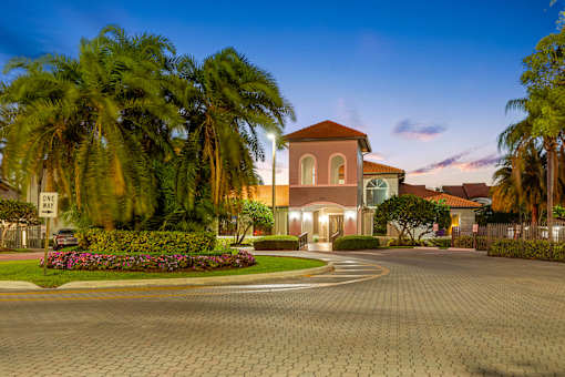 A house with a driveway and palm trees in front.