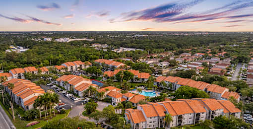A sunset view of a residential area with houses and a pool.