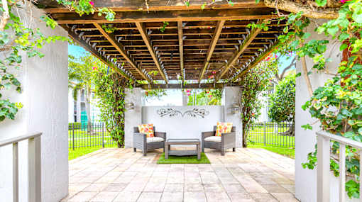 A patio with a couch and a table under a pergola.