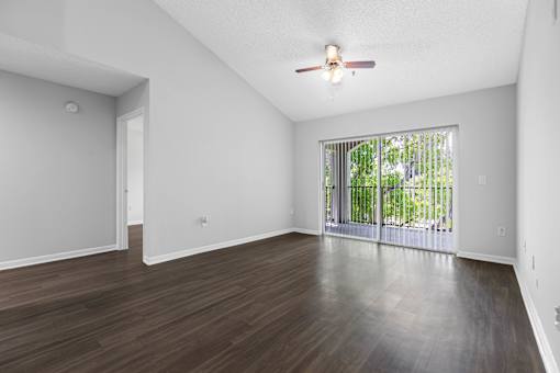 A room with a ceiling fan and sliding glass doors.