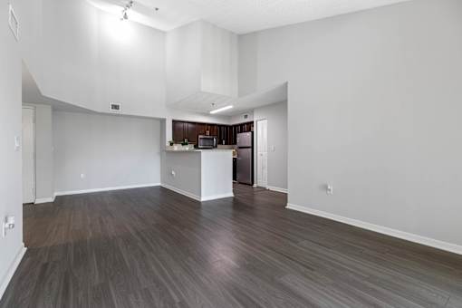 A spacious room with wood flooring and white walls.