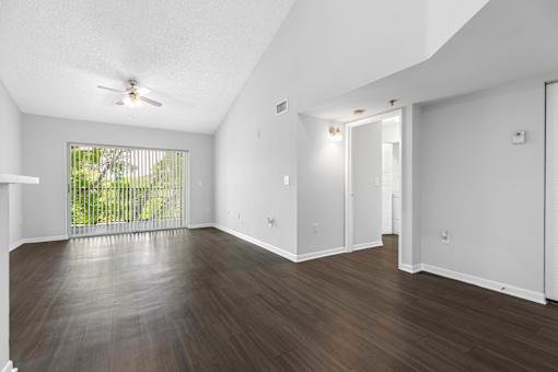 A room with a slanted ceiling and a window with a view of a fence.