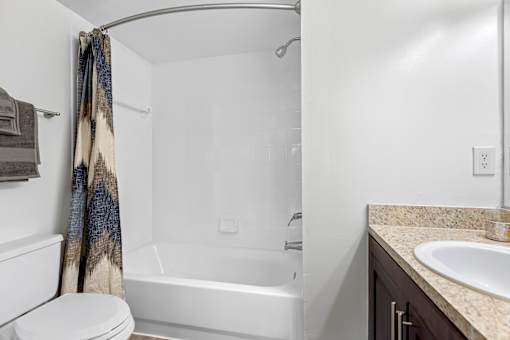 A white toilet sits next to a white bathtub in a bathroom.