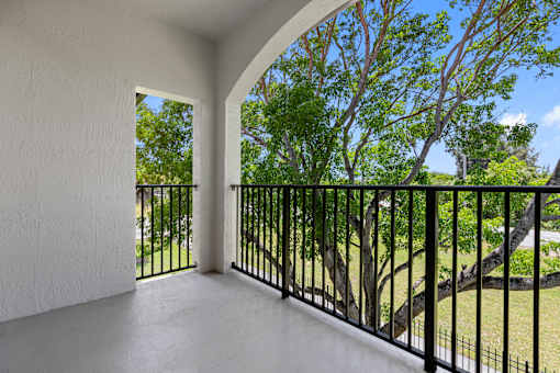 A balcony with a black railing and a view of trees.