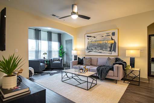 A living room with a grey couch and a painting on the wall.