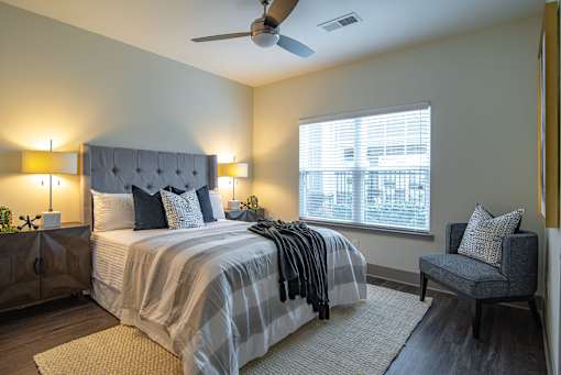 A bedroom with a bed, chair, and ceiling fan.