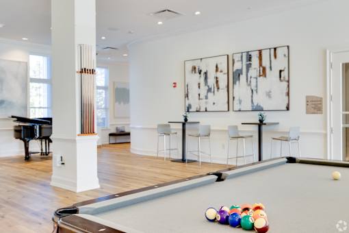 A pool table with a few balls on it in a room with a piano.