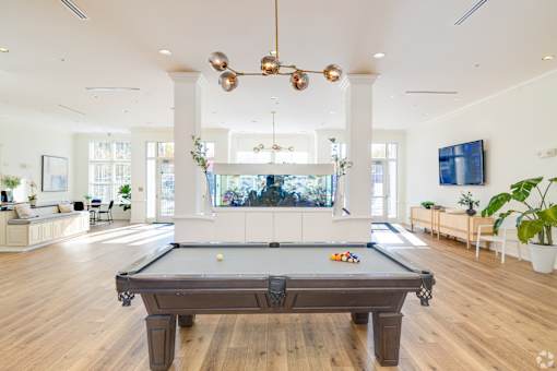A pool table is in the middle of a room with a TV on the wall.